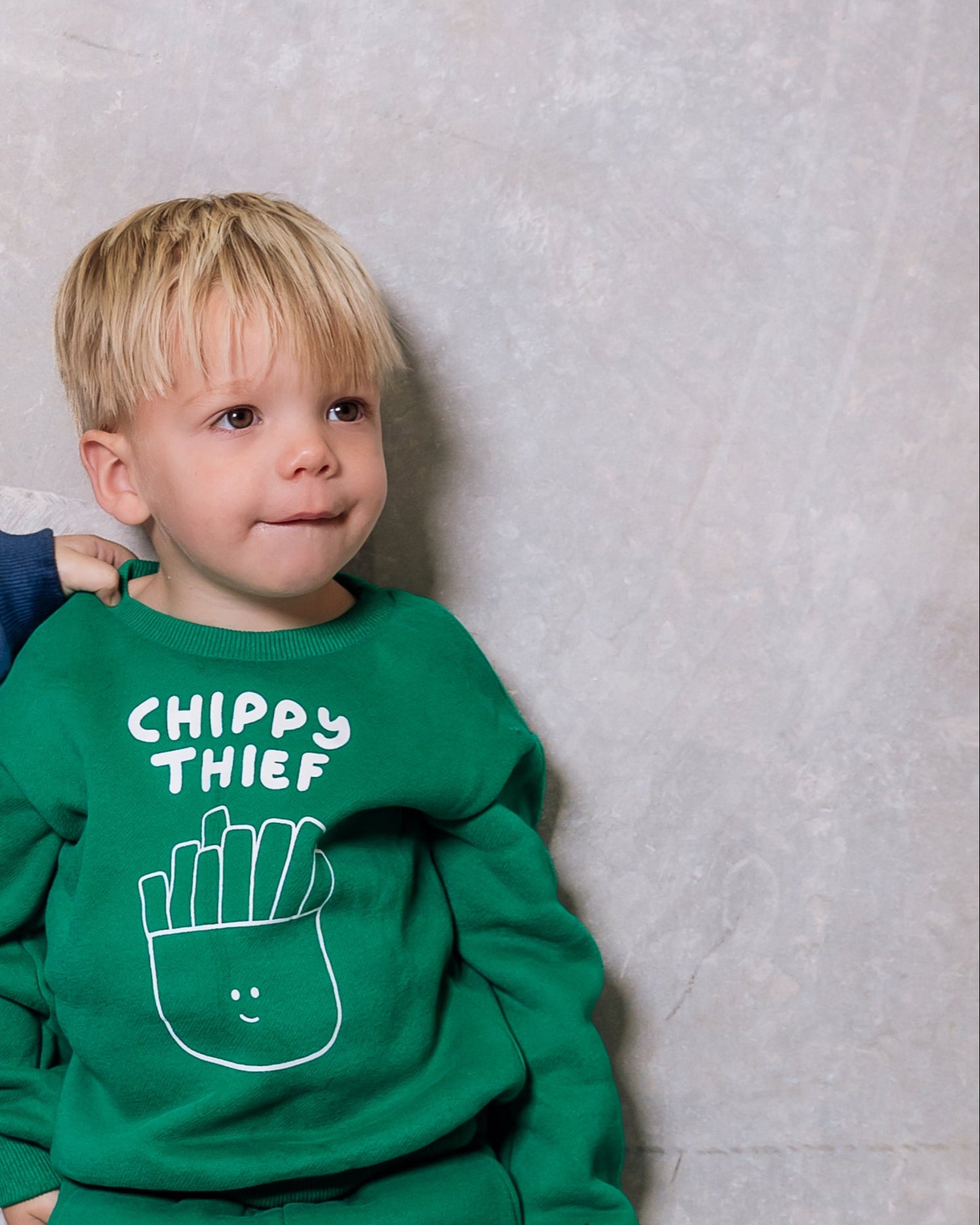 Two children wearing blue and green pajamas with text and graphics against a plain background