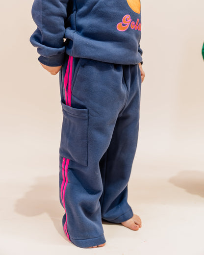 Person wearing a blue tracksuit with pink stripes on a plain background