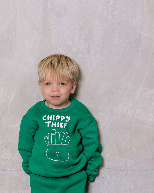 Child wearing a green outfit with text against a plain background