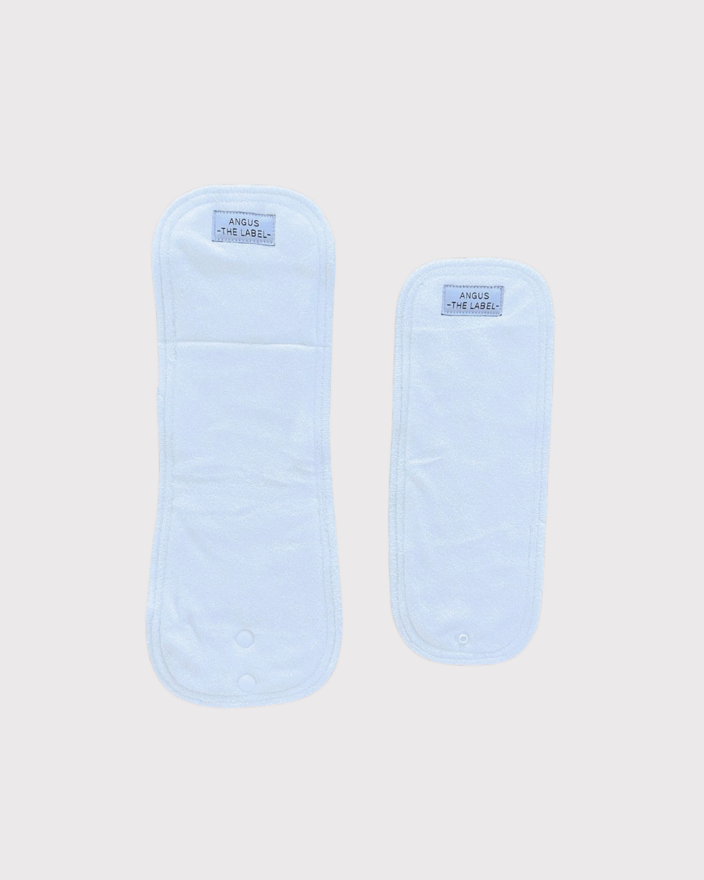 Two reusable nappy inserts in different sizes, made from soft, absorbent fabric, featuring the Angus The Label logo, designed for eco-friendly and sustainable diapering solutions.